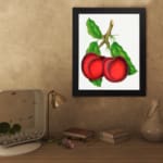 Vintage wall art featuring two red plums with green leaves on a white background. displayed on the wall