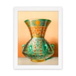 Vintage wall art featuring a decorative green vase with floral and geometric patterns, framed in white. hung on the wall