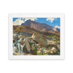 Vintage wall art of a mountain landscape with a waterfall, earthy rocks, green hills, and a blue sky with white clouds. hung on the wall