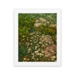 Vintage wall art of white wildflowers in a green field with stones, framed in black. hung on the wall