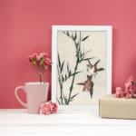 Infidu vintage wall art with two birds flying near bamboo in soft tones. displayed on the wall