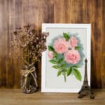 Infidu vintage wall art featuring pink roses with green leaves and a soft blue watercolor background. displayed on the wall