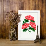 Infidu vintage wall art featuring delicate pink flowers and vibrant green leaves against a white background with a sleek black frame. displayed on the wall art in a black frame