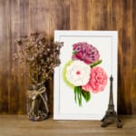 Infidu vintage wall art featuring three large flowers in purple, white, and coral pink with green leaves and a soft watercolor background. displayed on the wall