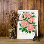 Vintage pink rose wall art with green leaves and trellis design. displayed on the wall