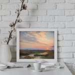 Infidu vintage wall art featuring a peaceful landscape at sunrise with soft blue, pink, and orange skies over lush green fields and distant hills. displayed on the wall art in a white frame