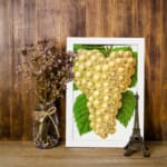 Vintage art of golden yellow grapes with green leaves on a white background. displayed on the wall