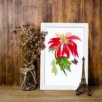 Vintage wall art print of a red flower with peach petals, green leaves, and a black and purple butterfly on a white background. displayed on the wall