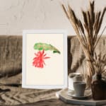 Vintage wall art with a red hanging flower and green leaf on a cream background, framed in white. displayed on the wall