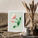 Vintage botanical wall art with a blooming flower and detailed green leaves, framed in white. displayed on the wall
