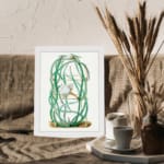Vintage botanical wall art of a cactus with twisting green stems and a white flower, framed in white. displayed on the wall