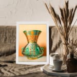 Vintage wall art featuring a decorative green vase with floral and geometric patterns, framed in white. displayed on the wall