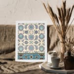 Vintage Persian floral and geometric wall art print with blue, teal, and purple flowers on a cream background in a white frame. displayed on the wall
