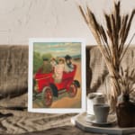 Vintage wall art of red antique car with four people in early 20th-century clothing, riding through the countryside. displayed on the wall in a white frame