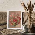 Vintage wall art of red roses and pink flowers with green leaves on a beige background, framed in white. displayed on the wall