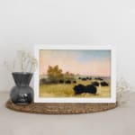 Infidu vintage wall art featuring a calm pastoral scene with black cattle grazing on a green field under a soft, cloudy sky. displayed on the wall art in a white frame