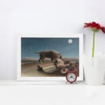 Infidu vintage wall art featuring a mysterious scene of a lion standing beside a sleeping person under a full moon in a serene, dreamlike landscape. displayed on the wall art in a white frame