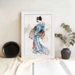 Vintage wall art of a Japanese woman in a soft blue kimono with a fan, styled with calm brush strokes and traditional details. displayed on the wall