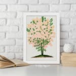 Infidu vintage wall art of a delicate pink blossom tree with green leaves and a white background. displayed on the wall