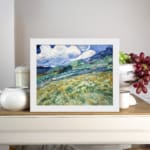 Infidu vintage countryside wall art with green hills and swirling blue sky. displayed on the wall