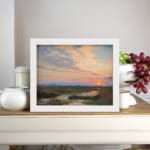 Infidu vintage wall art featuring a peaceful landscape at sunrise with soft blue, pink, and orange skies over lush green fields and distant hills. displayed on the wall art in a white frame