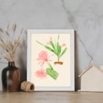 Vintage wall art with pink flowers and green cactus stems in a brown pot, set against a beige background with a clean white frame. displayed on the wall