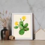 Vintage wall art featuring a cactus with yellow flowers, set against a light beige background with a white frame. displayed on the wall