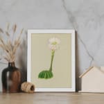 Vintage wall art with a round green cactus and a tall white flower with pink and yellow accents, on a beige background, framed in white. displayed on the wall