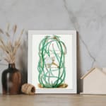 Vintage botanical wall art of a cactus with twisting green stems and a white flower, framed in white. displayed on the wall