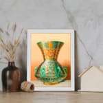 Vintage wall art featuring a decorative green vase with floral and geometric patterns, framed in white. displayed on the wall