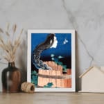 Vintage wall art of a ghostly face with long black hair emerging from a wooden barrel, with a dramatic night sky background. displayed on the wall in a white frame