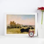 Infidu vintage wall art featuring a calm pastoral scene with black cattle grazing on a green field under a soft, cloudy sky. displayed on the wall art in a white frame