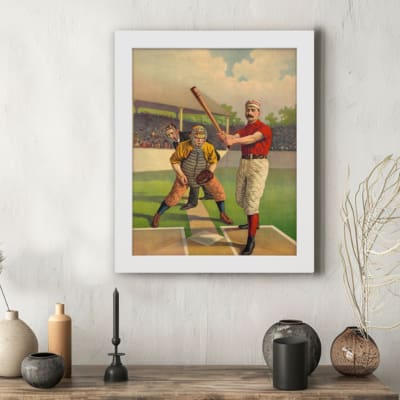 Infidu vintage wall art featuring a classic baseball scene with a batter, catcher, and judge in period uniforms on a vibrant field. displayed on the wall in a white frame