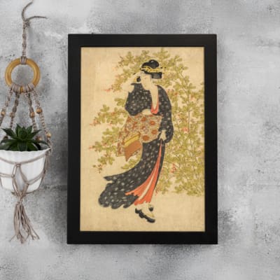 Vintage Japanese wall art of a woman in a kimono with floral patterns, set against a soft green and beige background. displayed on the wall in a black frame