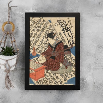 Vintage Japanese ukiyo-e wall art of a scholar writing on a scroll, with intricate calligraphy in the background. displayed on the wall in a black frame