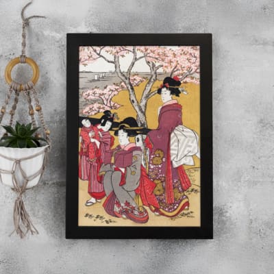 Vintage Japanese wall art with elegantly dressed women in kimonos, intricate patterns, and cherry blossom trees in a serene setting. displayed on the wall in a black frame