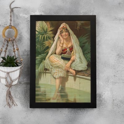 Vintage wall art of a woman sitting by a peaceful pool, surrounded by tropical plants, wearing traditional attire with a headscarf and jewelry. displayed on the wall