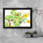 Vintage floral wall art with yellow flowers, green leaves, and a black frame on a white background. displayed on the wall