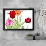 Vintage floral wall art with red, pink, and orange tulips, green leaves, and a black frame on a white background. displayed on the wall