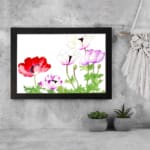 Vintage floral wall art with red, purple & white flowers, green leaves, and a black frame on a white background. displayed on the wall