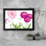 Vintage floral wall art featuring pink and purple flowers with green leaves, set against a white background with a black frame. displayed on the wall