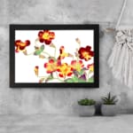 Vintage floral wall art with red, yellow, and orange flowers, green leaves, and a black frame on a white background. displayed on the wall