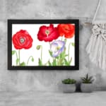 Vintage floral wall art with red and purple-white poppies, green leaves, and a black frame on a white background. displayed on the wall