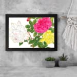 Vintage floral wall art with pink, yellow, and white roses, green leaves, and a black frame on a white background. displayed on the wall