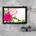 Infidu Vintage Floral Wall Art with pink, cream, and white flowers, green leaves, and a black frame on a white background. displayed on the wall