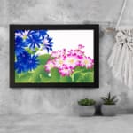 Infidu Vintage Floral Wall Art with deep blue and pink flowers, bright green leaves, a white background, and a black frame for a classic touch. displayed on the wall