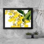 Vintage floral wall art with yellow flowers and green leaves in a black frame. displayed on the wall