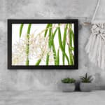 Vintage floral wall art with white orchids and green leaves, framed in black for a classic and elegant look. displayed on the wall
