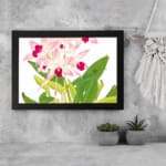 Vintage floral wall art with soft pink orchids, dark pink centers, green leaves, and a black frame on a white background. displayed on the wall