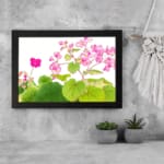 Infidu Vintage Floral Wall Art with pink flowers and green leaves on a white background, framed in black for a classic and elegant look. displayed on the wall.